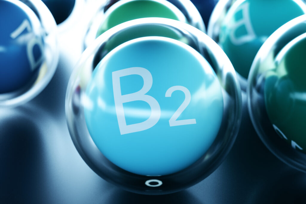 Vitamin B1 Schriftzug auf hellblauem Ball umrandet von einem durchsigtigen Ball auf schwarzem Boden
