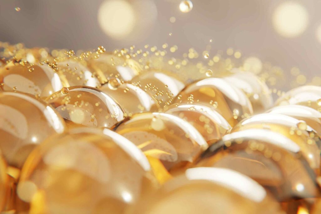 Abstrakte Nahaufnahme von golden glänzenden Flüssigkeitstropfen die Licht reflektieren.