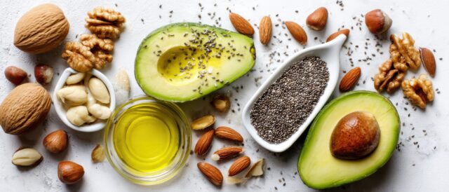 Avocado, Nüsse, Samen und Öl auf weißem Untergrund