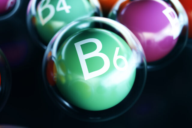 Vitamin B6 Schriftzug auf gründem Ball umrandet von einem durchsigtigen Ball auf schwarzem Boden.