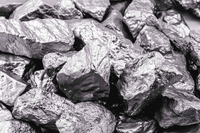 Ein massiver Block aus gräulich-glänzendem Molybdän-Metall in einer industriell-ästhetischen Nahaufnahme.